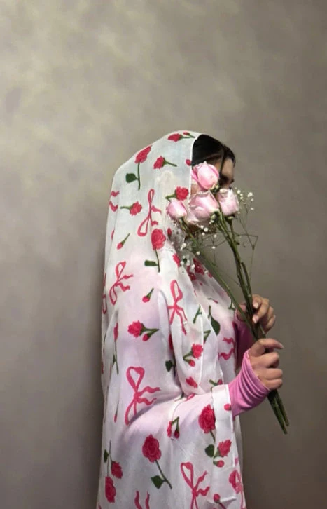 Model wearing a floral hijab, holding pink roses